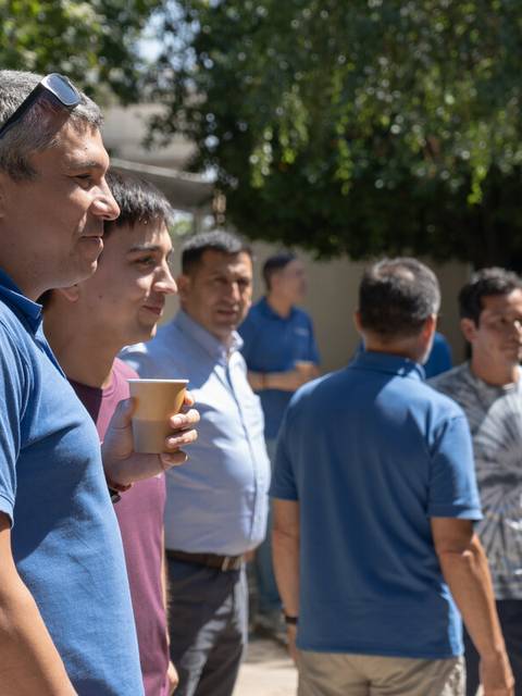 Un grupo de hombres conversando al aire libre en un evento social.