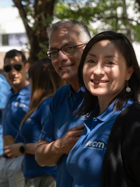 Un grupo de personas sonrientes vestidas con camisetas de color azul posan al aire libre.