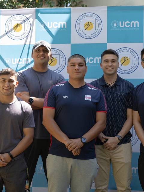 Un grupo de seis jóvenes posando frente a un fondo con el logo de la UCM.
