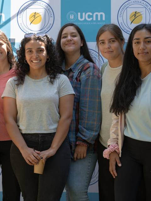 Un grupo de mujeres posando sonrientes frente a un fondo que representa a una institución educativa.