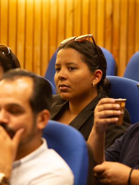 Un grupo de personas sentadas en un auditorio prestando atención a un evento.