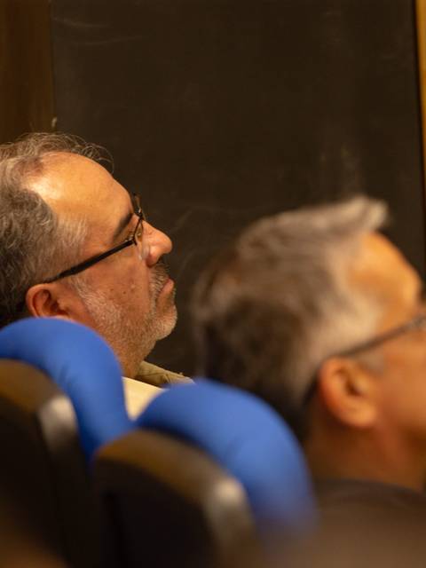 Un grupo de personas sentadas en un auditorio, prestando atención a una presentación.