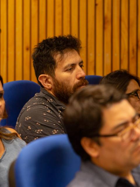 Un grupo de personas sentadas escuchando atentamente en una sala.