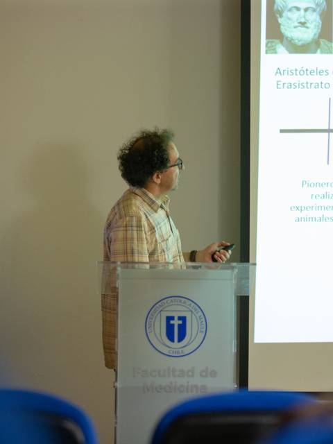 Un presentador expone información sobre filósofos y médicos en una conferencia académica.