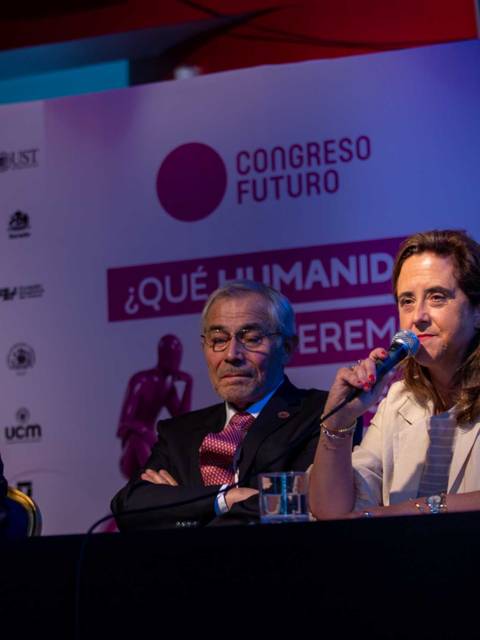 La imagen muestra a tres personas en un panel de discusión en un congreso sobre el futuro de la humanidad.