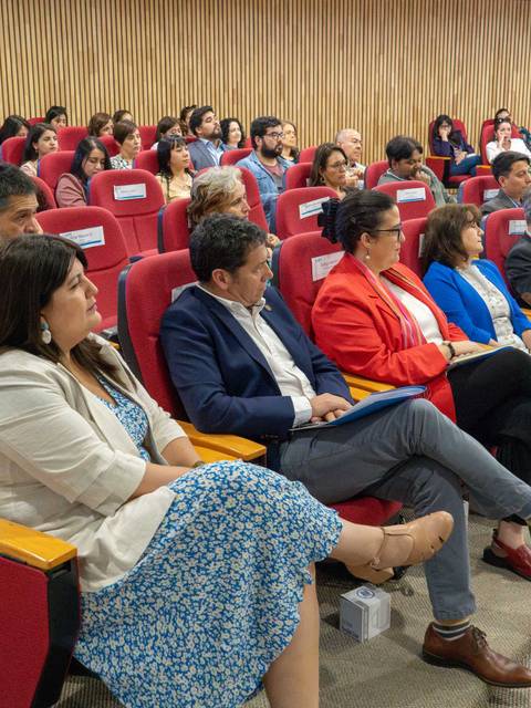 Una audiencia sentada en un auditorio, prestando atención a una presentación.