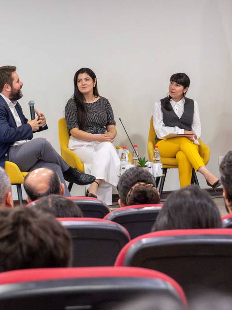 Un panel de discusión con varios ponentes en un auditorio.