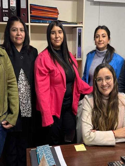 Un grupo de seis mujeres posando juntas en una oficina.