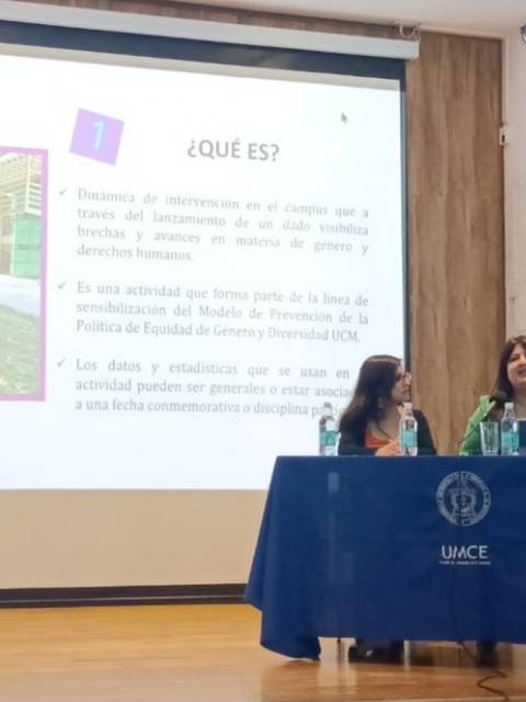 Una charla educativa sobre equidad de género con tres ponentes frente a una presentación en pantalla.