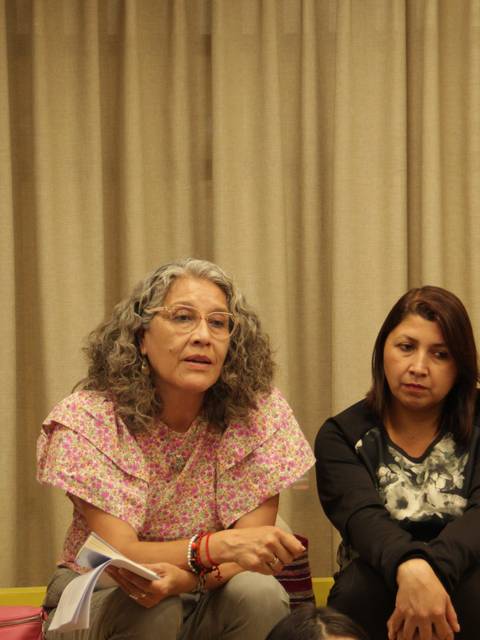 Un grupo de cuatro personas sentadas en una conversación seria en un ambiente interior.