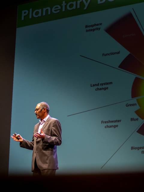 Un presentador explica un gráfico sobre los sistemas planetarios en un evento.