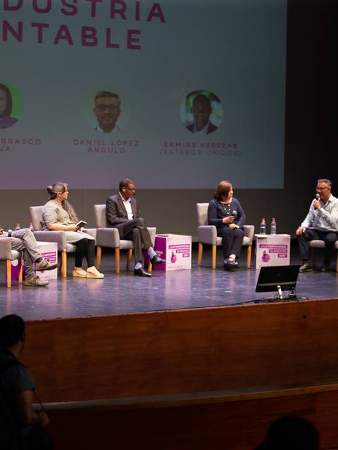 Un panel de discusión sobre la industria sustentable con varios participantes en un escenario.