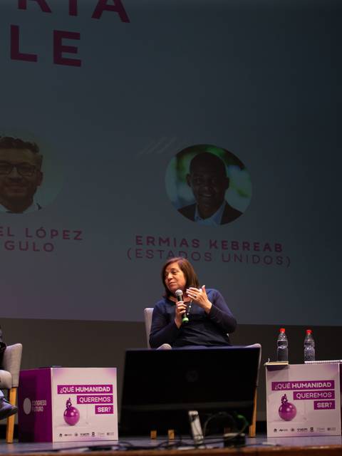 Un panel de discusión en un evento donde varios participantes están sentados en el escenario compartiendo ideas.