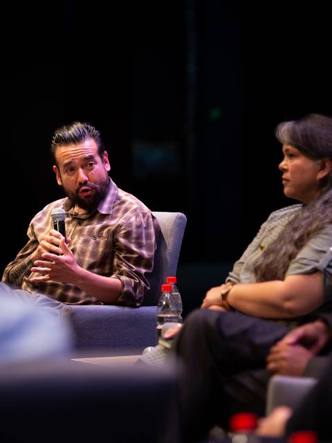 Un panel de discusión con varios participantes sentados en un escenario hablando sobre un tema relevante.