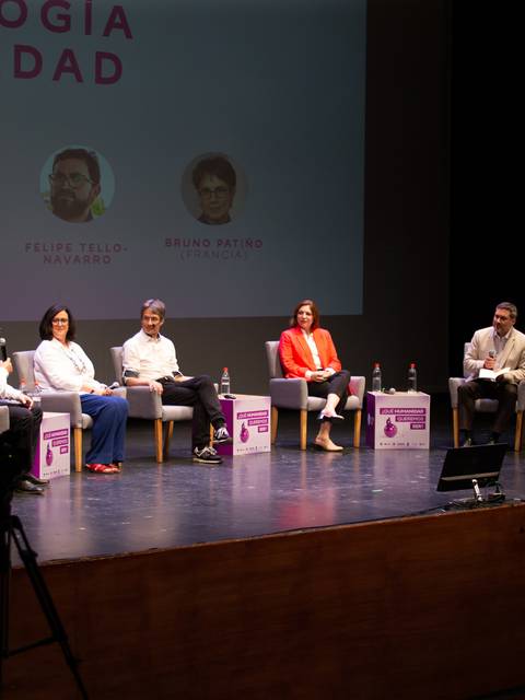 Un panel de discusión sobre tecnología y sociedad con varios participantes en el escenario.