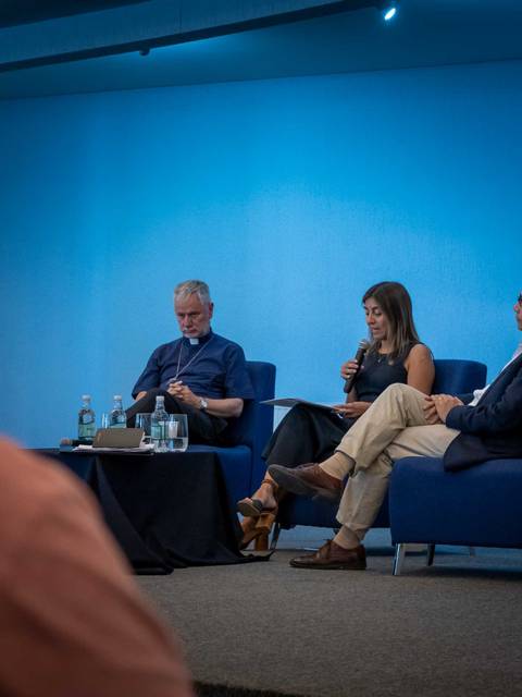 Tres personas discuten en un panel en un ambiente luminoso y moderno.