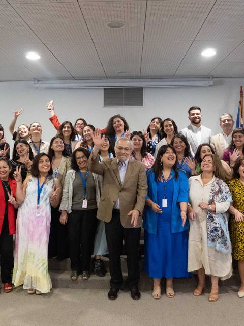 Un grupo de personas sonrientes en una sala levantando las manos en señal de celebración.