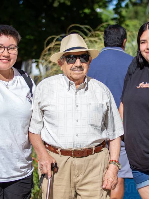 Tres personas sonríen juntas en un entorno al aire libre.