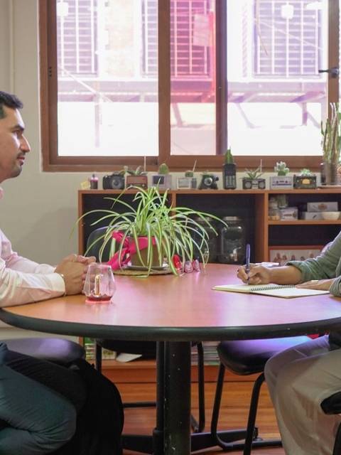 Una pareja de personas conversando en una mesa en una oficina.