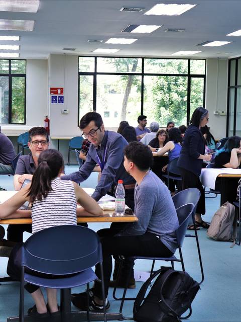 Un grupo de personas conversando y trabajando en equipo en una sala de estudio.