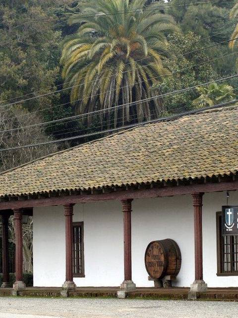 Una casa de estilo colonial con palmeras al fondo.