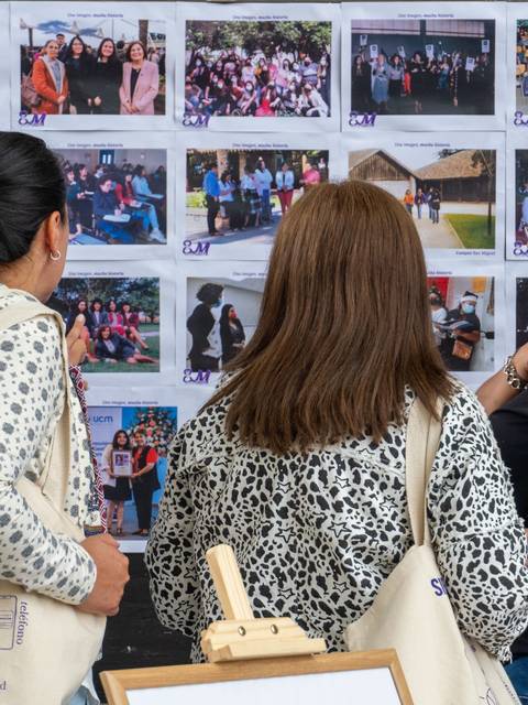 Un grupo de mujeres observa varias fotos en una exposición.