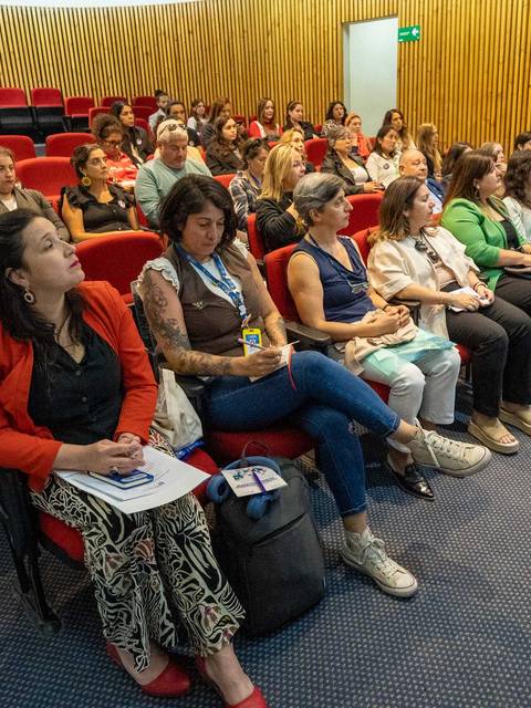 Una gran cantidad de personas sentadas escuchando atentamente en una conferencia.