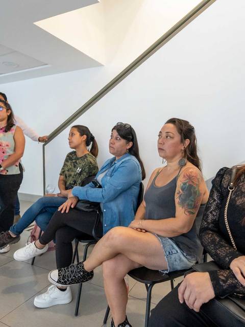 Un grupo de personas sentadas en una sala de espera, observando atentamente.