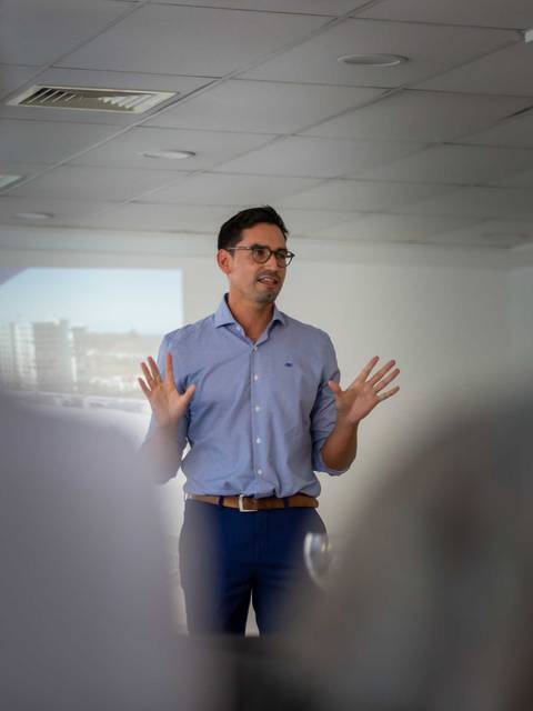 Un hombre está dando una charla en una sala de reuniones con proyector.