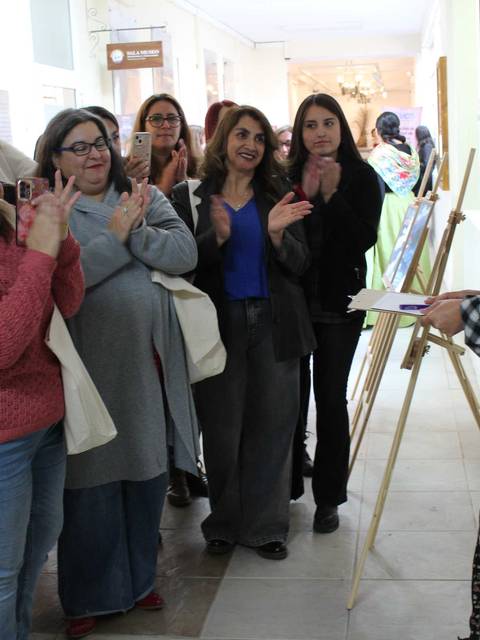 Un grupo de mujeres aplaude mientras una artista presenta su obra en una exposición.