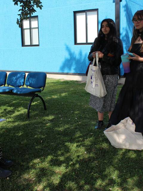 Un grupo de mujeres conversando en un espacio al aire libre con un fondo colorido.