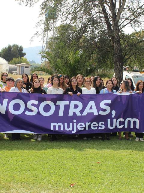 Un grupo de mujeres se reúne sosteniendo una pancarta en un evento en la UCM.
