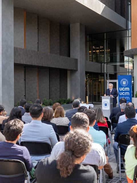 Un grupo de personas observa atentamente un evento al aire libre en un edificio moderno.