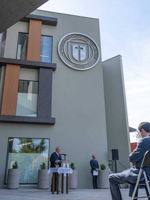 Una ceremonia al aire libre frente a un edificio moderno con un logo en la fachada.