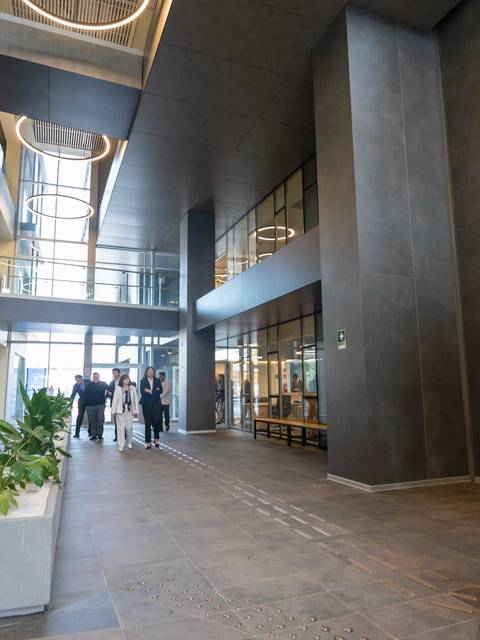 Una moderna oficina con personas caminando y plantas decorativas.