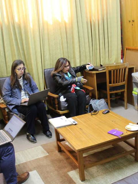 Un grupo de personas trabajando en una sala con laptops y tazas de café.
