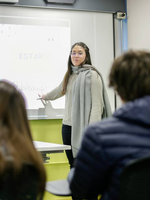 Una profesora está explicando un tema en clase con entusiasmo.