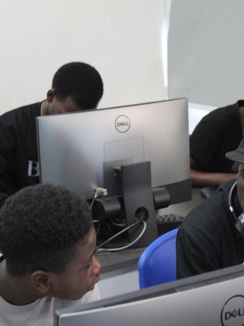 Un grupo de jóvenes trabajando en computadores en un ambiente de clases.