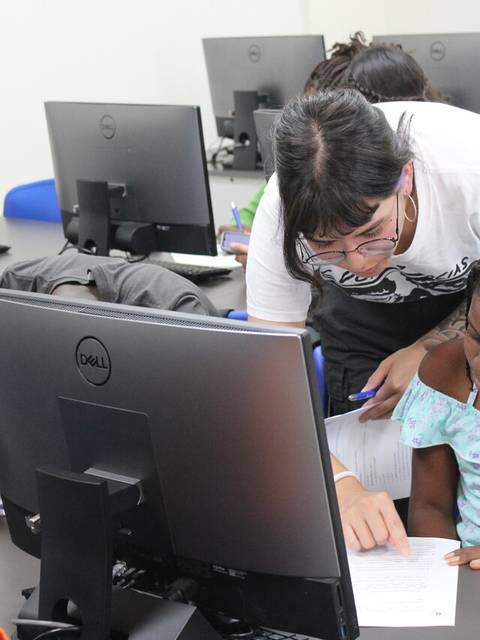 Un grupo de estudiantes recibe apoyo en una sala de computación.