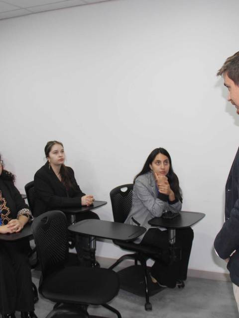 Un grupo de profesionales escucha atentamente a un expositor en una sala de clases.