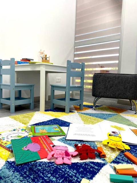 Un rincón de juegos para niños con libros y peluches en el suelo.