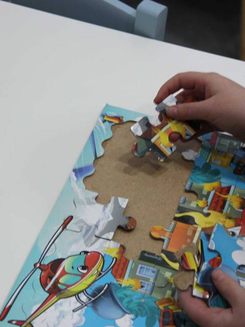 Un niño está armando un rompecabezas colorido con piezas de diferentes formas.