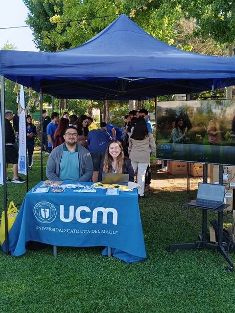 Feria universitaria de la Universidad Católica del Maule con estudiantes promocionando su oferta educativa.