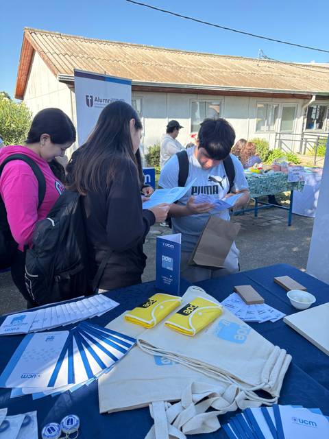 Un grupo de estudiantes en un evento con stands informativos.