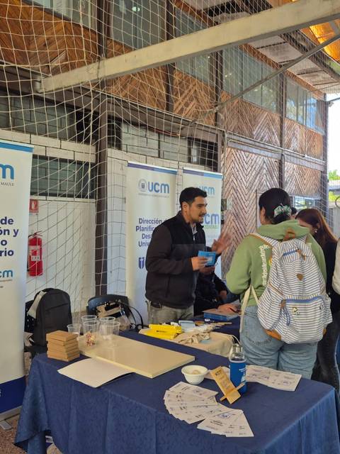 Un grupo de personas interactuando en un stand de información universitaria.