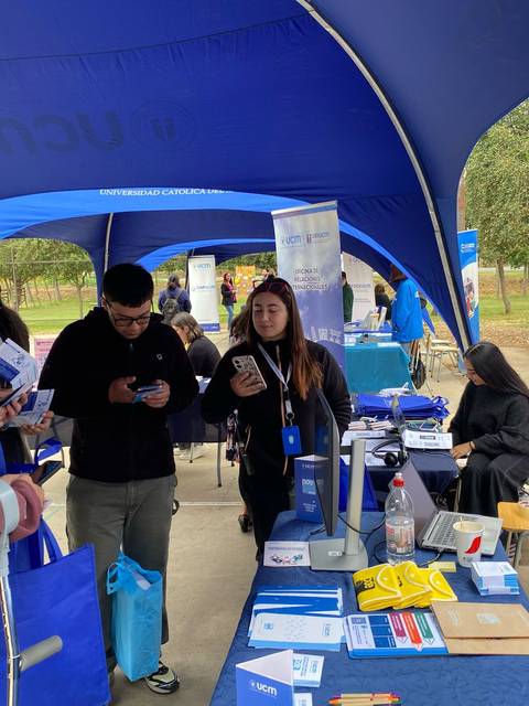 Un grupo de jóvenes interactuando en un evento al aire libre bajo carpas.
