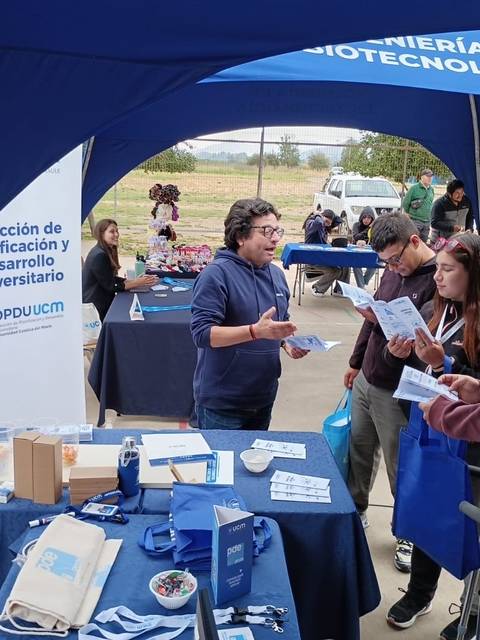 Un grupo de personas participando en una feria de información universitaria en un ambiente al aire libre.