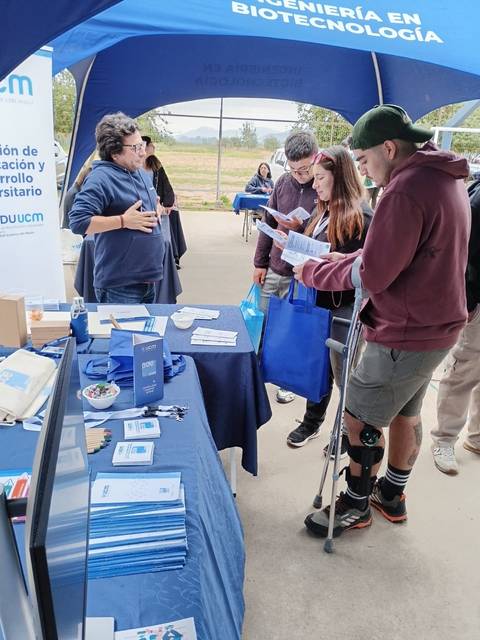 Feria informativa sobre biotecnología con estudiantes interactuando en un stand.