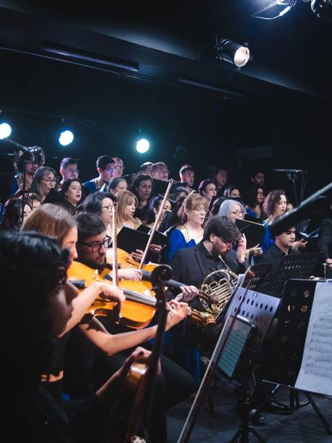 Un grupo de músicos y cantantes se presenta en un escenario iluminado.