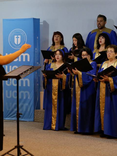 Un coro compuesto por varias personas en vestimenta azul, cantando bajo la dirección de una mujer.